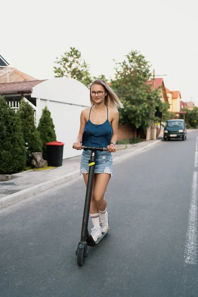 Millennial donna cavalcando uno scooter elettrico in strada — Foto Stock