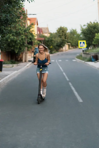 Milenial mujer montando un scooter eléctrico en la calle —  Fotos de Stock