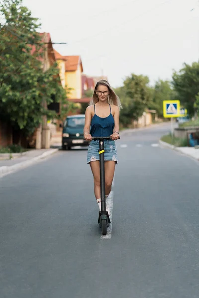 Milenial mujer montando un scooter eléctrico en la calle —  Fotos de Stock