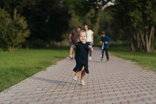 Malá dívka běží, zatímco její rodina sleduje ji — Stock fotografie