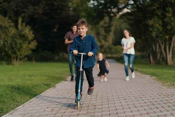 Niño de la escuela montando un scooter en el parque —  Fotos de Stock