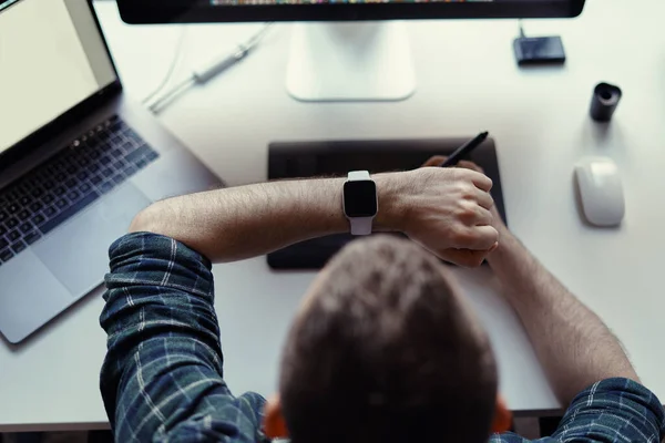 Hombre viendo reloj inteligente mientras trabaja — Foto de Stock