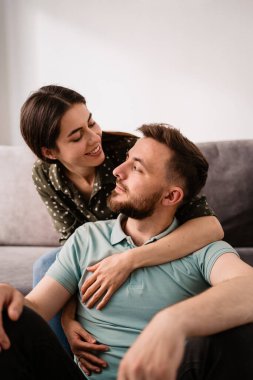 Kanepede birbirine gülümseyen erkek ve kadın portresi.