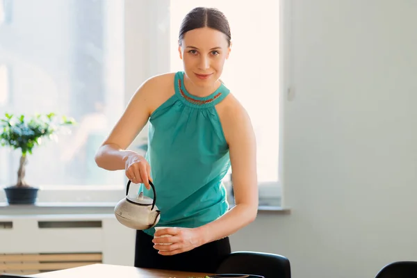 Una mujer encantadora con una tetera en sus manos vertiendo té — Foto de Stock