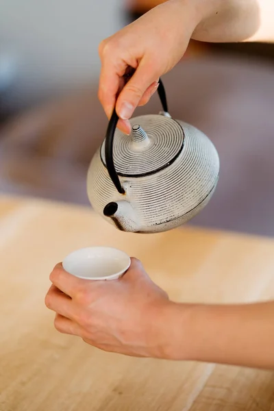 Mani donna con una teiera versando il tè — Foto Stock