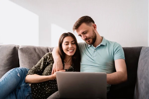 Hombre y mujer sentados en un sofá con un portátil — Foto de Stock