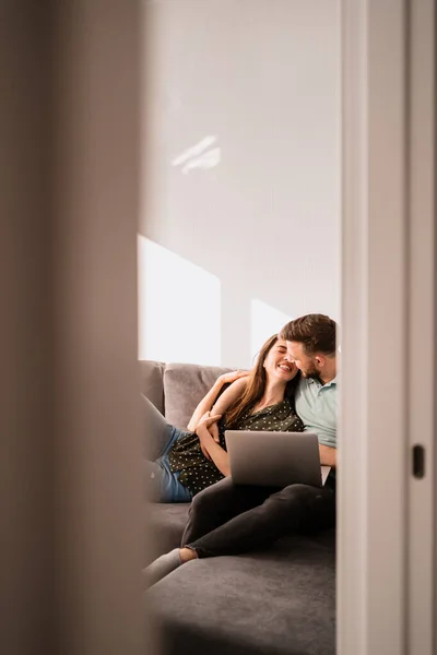 Hombre y mujer sentados en un sofá con un portátil — Foto de Stock