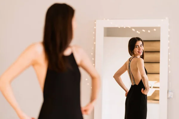 Леди носит красивое черное платье, смотрящее в зеркало — стоковое фото