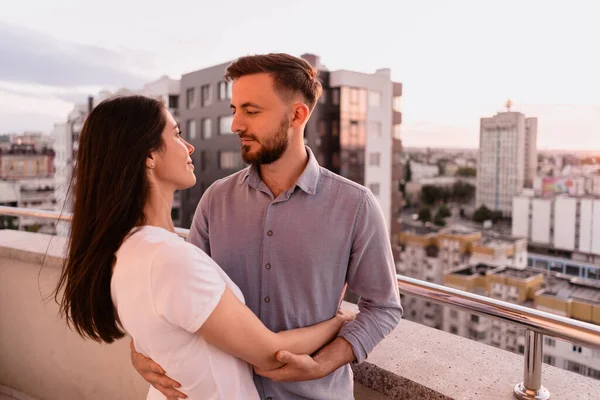 Homme et femme sur le balcon au coucher du soleil dans la ville — Photo