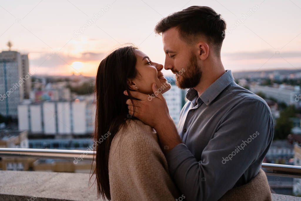 Man and woman on balcony at sunset in the city