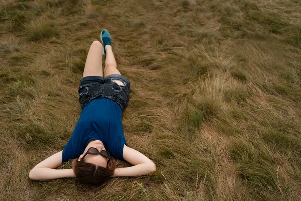 Woman with sunglasses and shorts lying in the grass — Stock Photo, Image