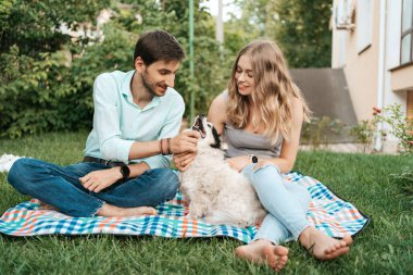 Çimlerin üzerinde köpeği olan güzel bir çift.