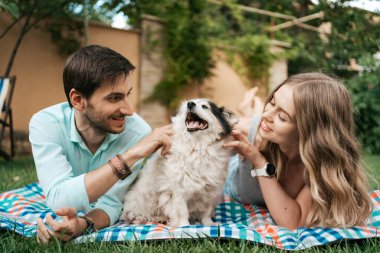Çimlerin üzerinde köpeği olan güzel bir çift.