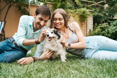 Çimlerin üzerinde köpeği olan güzel bir çift.