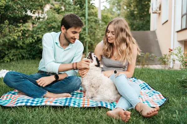 Gyönyörű pár egy kutyával a füvön — Stock Fotó