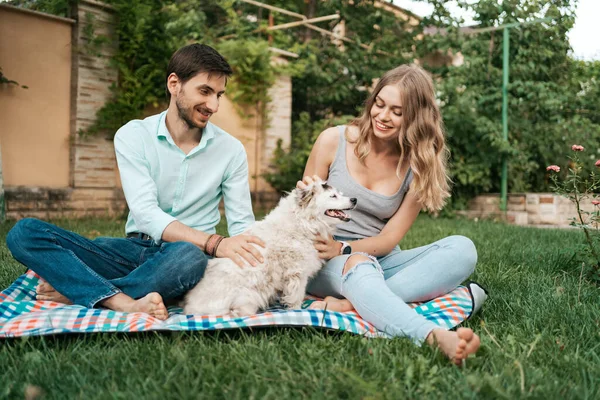 Belo casal com um cão na grama — Fotografia de Stock