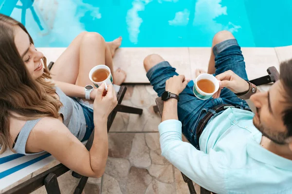 Hombre y mujer pasan tiempo juntos cerca de la piscina tomando té —  Fotos de Stock