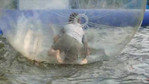 Kinder haben Spaß auf dem Spielplatz. Kind in Natrium, Wasserball. Der kleine Junge wird auf dem Spielplatz unterhalten. Junge schwimmt. Ball mit Luft aufgeblasen und ein Mann drinnen. — Stockvideo