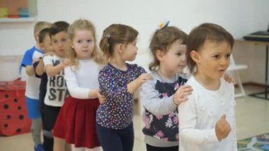 Çocuk oyun odası geliştirmek. Sınıflar eğlenceli sırasında duygular genç çocuk. Çocuk komşular omuzlarına ellerini koymak ve mutlu bir şekilde birbiri ardına taşıma.