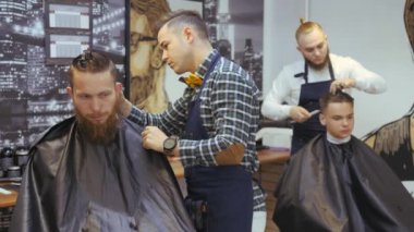Kuaför erkekler için. Berber dükkanı. Saç bakımı için genç bir adam. Kuaför bir saç kesimi ile bir saç modeli için sakallı bir adam için çalışıyor. Bir hipster yaşam kavramı. Bir kesme makinesi ile Kuaför