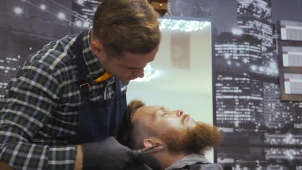 Peluquería para hombres. Barbería. Cuidando la barba. Un peluquero con un corte de pelo trabaja sobre la barba y el bigote de un tipo barbudo. El concepto de un estilo de vida hipster. Cliente Hipster obtiene un — Vídeo de stock