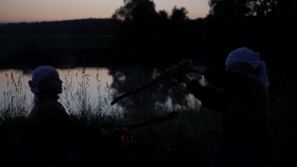 Étincelles de bâtons brûlants. Bataille d'enfants à dubankah brûlant. les enfants luttent contre le fond de la rivière. Les charbons provenant de la combustion des bâtonnets se dispersent dans différentes directions. Mouvement lent — Video