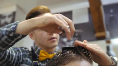Kuaför erkekler için. Berber dükkanı. Kuaför bir saç kesimi ile bir saç modeli için sakallı bir adam için çalışıyor. Bir hipster yaşam kavramı. Kuaför kesim saç istemcileri kafasına çivi ile. Müşteri