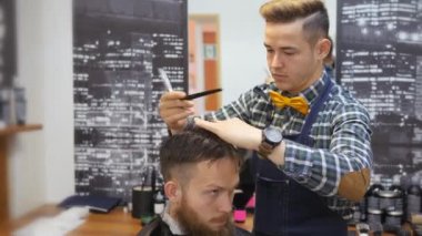 Kuaför erkekler için. Berber dükkanı. Kuaför bir saç kesimi ile bir saç modeli için sakallı bir adam için çalışıyor. Bir hipster yaşam kavramı. Kuaför kesim saç istemcileri kafasına çivi ile. Müşteri