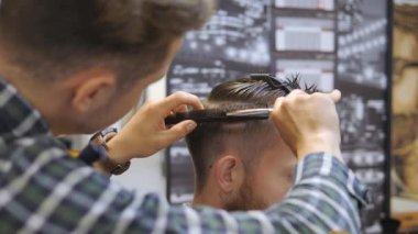 Kuaför erkekler için. Berber dükkanı. Kuaför bir saç kesimi ile bir saç modeli için sakallı bir adam için çalışıyor. Bir hipster yaşam kavramı. Kuaför kesim saç istemcileri kafasına çivi ile. Müşteri