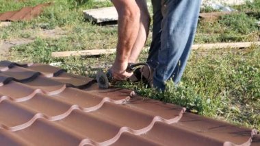 Çatı malzemesi ile çalışır. çatı metal. Kesme profil metal elektrik Bulgarca. El kesici alet metal daire altından kıvılcımlar. çatı malzemesi yaprak yeşil çim üzerinde yalan