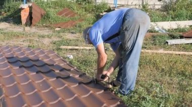 Çatı malzemesi ile çalışır. çatı metal. Kesme profil metal elektrik Bulgarca. El kesici alet metal daire altından kıvılcımlar. çatı malzemesi yaprak yeşil çim üzerinde yalan