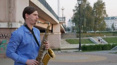 Saksofoncu trompet çalıyor. Şehir setin. yukarı şehrin sokaklarında bir enstrüman çalma bıyıklı bıyıklı adam. müzisyen köprünün altından bir müzik aleti çalıyor.