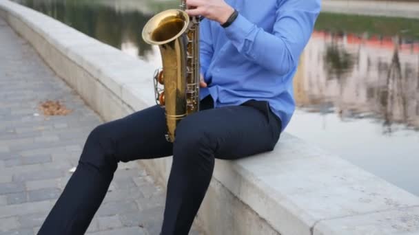 Saxofonista toca trompete. City Embankment. um homem com bigode a tocar um instrumento musical nas ruas da cidade . — Vídeo de Stock