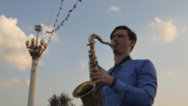 Saxofonista toca trompete. City Embankment. um homem com bigode a tocar um instrumento musical nas ruas da cidade . — Vídeo de Stock