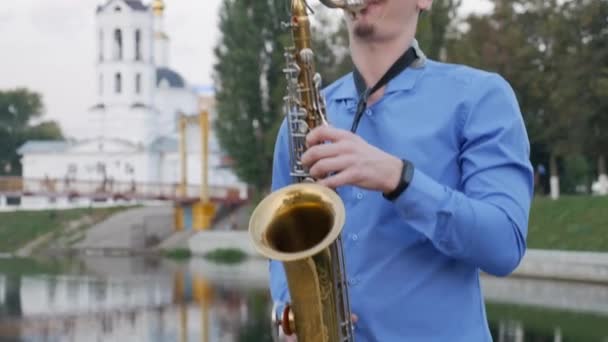 Saxofonist spielt Trompete. Stadtdamm. Mann mit Schnurrbart, der auf den Straßen der Stadt ein Musikinstrument spielt. Saxophonlinton — Stockvideo