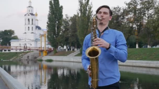 El saxofonista toca la trompeta. City Embankment. un hombre con bigote batido tocando un instrumento musical en las calles de la ciudad. saxofón Linton — Vídeos de Stock