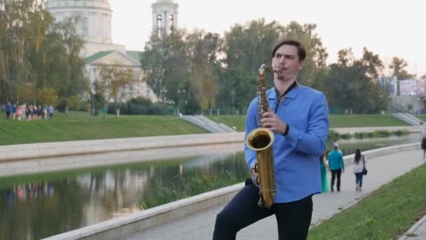 Saxofonist spielt Trompete. Stadtdamm. Mann mit Schnurrbart spielt auf den Straßen der Stadt ein Musikinstrument. — Stockvideo