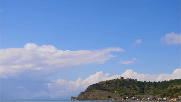 Montanhas contra o céu azul com nuvens brancas. As nuvens circulares atravessam o céu azul. As melhores vistas da costa. Bela vista do mar. melhor vídeo da costa montanhosa. melhor lugar para um — Vídeo de Stock