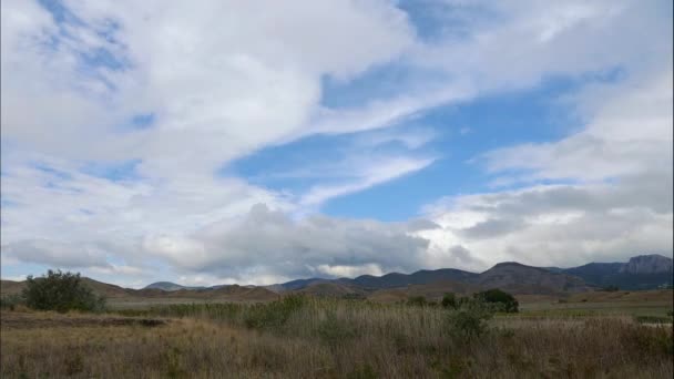 Montanhas contra o céu azul com nuvens brancas. As nuvens circulares atravessam o céu azul. melhor lugar para umas férias em família . — Vídeo de Stock