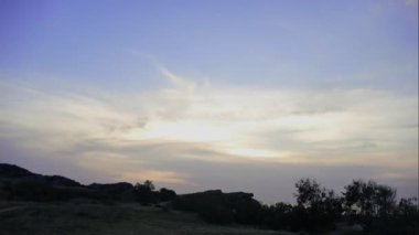 Arka planda gri bulutlar dağlar. Kara bulutlar dağlar başında örtmek. güneş dağların üzerinden ayarlar. Bozkır çim ve ağaç dalları fon karşı günbatımı. Şaşırtıcı