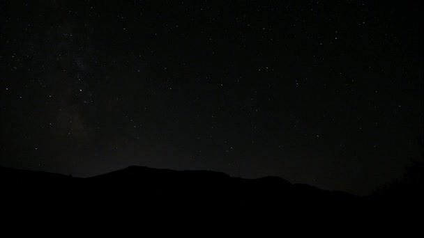 Cielo nocturno estrellado. Estrellas centelleantes en el oscuro cielo nocturno. Nubes claras a la deriva en el cielo nocturno. Atardecer sobre la montaña hreptom. Fascinante espectáculo. Caducidad — Vídeo de stock