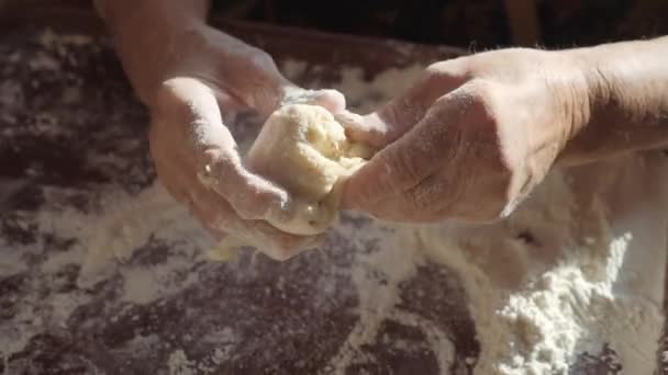 祖母の手は、ケーキを作る。しわの女性の手は、生地のボールをロールバックします。家庭の台所で生地をこねる. — ストック動画