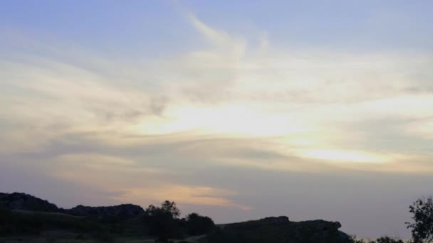 Montañas en el fondo de nubes grises. Nubes oscuras envuelven las cimas de las montañas. el sol se pone sobre las montañas. Hierba estepa y ramas de árboles contra el telón de fondo de la puesta del sol. Increíble. — Vídeo de stock