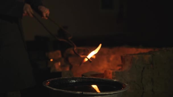 Smid werkt metaal. Werkman, de Highlander op particuliere smithy in het dorp. verharding van producten van metaal. Baden hete product in een container met koude olie. Olie flitsen open haard. Slow motion — Stockvideo