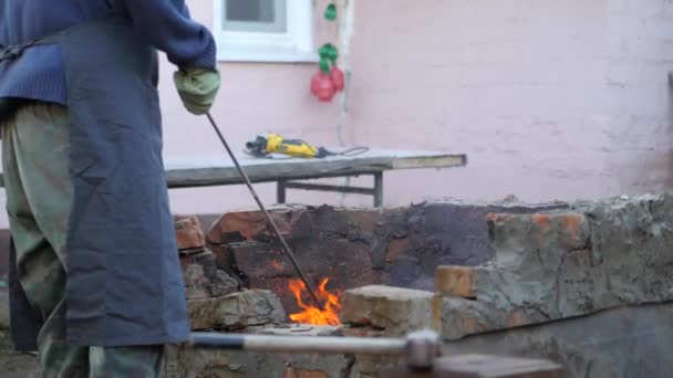 铁匠是金属公司的工作工匠, 村里私人铁匠上的高地人。工匠干扰炉内的余火。手都戴着防火手套。火花飞散。慢 — 图库视频影像