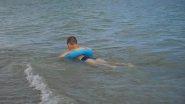 Çocuk bir daire içinde kıyı sallamak içinde yüzüyor.