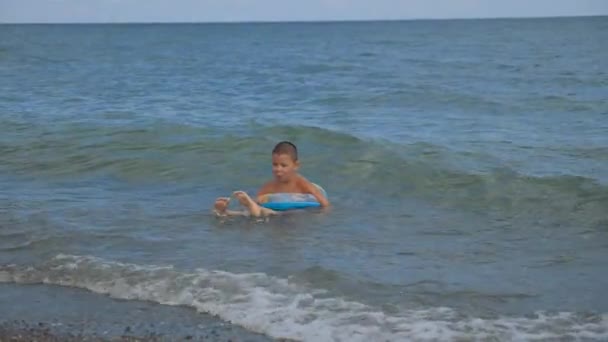 Niño está nadando en un círculo en la ola costera . — Vídeos de Stock