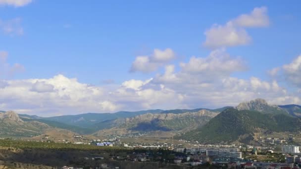 Γενοβέζικο φρούριο, Sudak, Κριμαία. Βουνά ενάντια στον γαλάζιο ουρανό με άσπρα σύννεφα. Σύννεφα Cirrus διασχίζουν το γαλάζιο του ουρανού. Κάτοψη της πόλης, τα βουνά, τα κτίρια και το δρόμο με πέρασμα — Αρχείο Βίντεο
