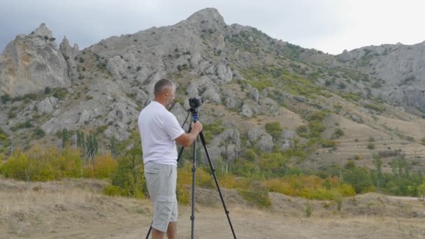 Kameramanların bir kamera üçayağa monte dağlardaki ateş eder. — Stok video