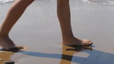 Çocuk sörf gidiyor. Arka plan çocuk ayağa dalgaların. deniz suyu uzak ayak izi yıkar